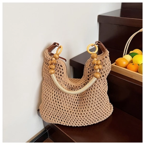 Detail of bohemian hollow knit tote bag with decorative wooden bead handle and leather joints