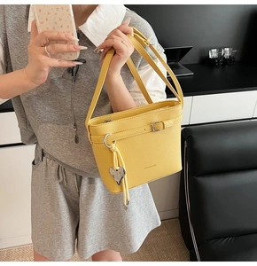 Detail of yellow lychee pattern leather handbag with metal buckle and heart pendant