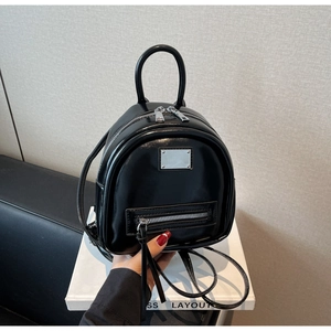 Close-up of black patent leather mini backpack with silver hardware and front pocket