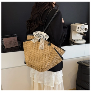 Détail d'un sac cabas en paille avec un nœud en dentelle blanche et des bords en cuir
