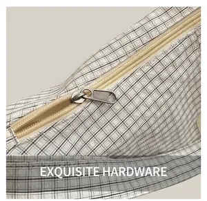 Detail of the high-quality metal zipper on a black and white plaid crossbody bag
