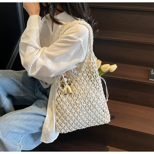 Detail of hollow woven tote bag with handle design and cute doll pendant decoration