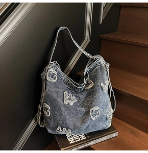 Close-up of vintage washed denim tote bag with distressed white letter embroidery