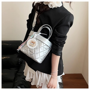 Detail of silver quilted bucket bag with wide strap and cute capybara charm