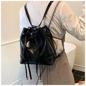 Side view of a glossy black PU leather bucket backpack with drawstring and metallic details