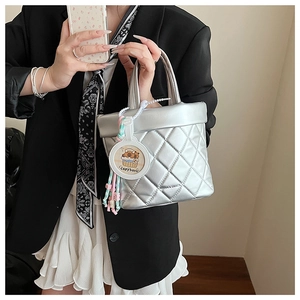 Detail of silver quilted bucket bag with a cute capybara pendant and beaded charm