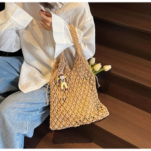 Detail of woven mesh tote bag with inner yellow pouch and cute girl doll pendant