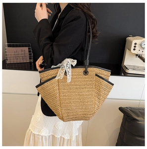 Détail du sac cabas en paille avec garniture en cuir noir et ruban en dentelle blanche
