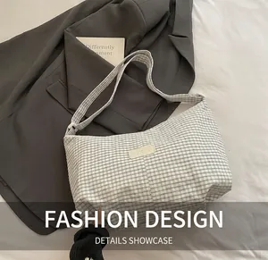Detail of a minimalist black and white checkered canvas shoulder bag with a brand label