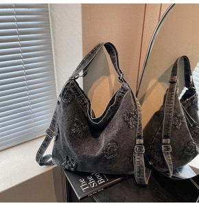 Detail of vintage washed black denim hobo bag with letter embroidery and silver buckle