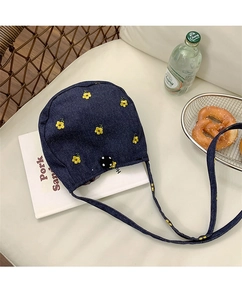 Détail d'un sac bandoulière en jean bleu orné de broderies florales jaunes
