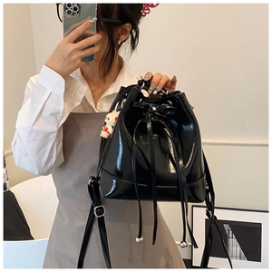 Detail of black glossy patent leather bucket bag with drawstring and silver metal beads