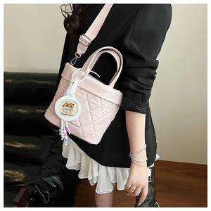 Detail of pink quilted bucket bag with wide strap and cute capybara pendant charm