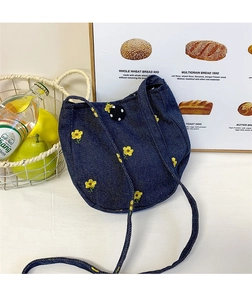Détail du sac bandoulière en denim bleu avec broderie florale jaune et bouton décoratif