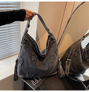 Detail of black washed denim hobo bag featuring frayed edges and vintage letter patches