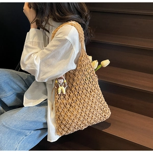 Detail of hand-woven hollow tote bag with astronaut pendant and floral decoration