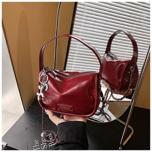 Detail view of burgundy leather handbag with chain strap and balloon dog charm