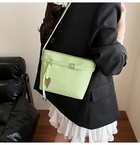 Detail of light green litchi texture bucket bag with leather strap and heart pendant