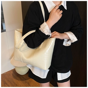 Detail showing high-capacity cream tote bag with crocodile texture and long shoulder straps
