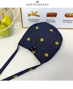 Gros plan de broderie de fleurs jaunes sur sac en jean bleu avec détail de bouton à pois