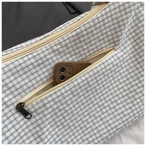 Close-up of minimalist black and white checkered crossbody bag with functional zip pocket