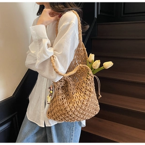 Detail of hand-woven hollow mesh tote bag in brown with floral tulip decoration