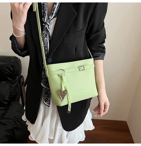 Detail of light green litchi grain bucket bag featuring silver buckle and heart tassel charm