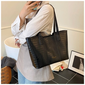 Model wearing a large black crocodile pattern tote bag for a professional commute look