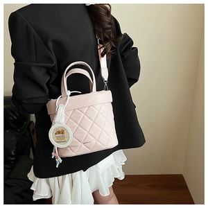 Detail of pink quilted handbag featuring stitched lattice and cute Capybara charm