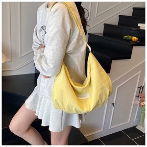 Detail of yellow nylon hobo bag showing textured fabric and stitched brand label