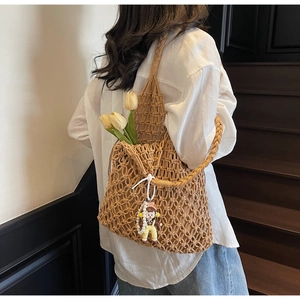 Detail of khaki crochet tote bag with hollow knit texture and cute plush charm pendant