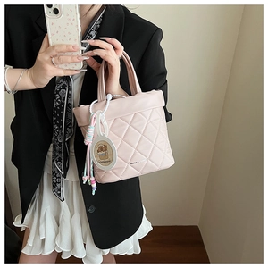 Detailed shot of pink quilted bucket bag featuring a cute capybara charm and rainbow beads