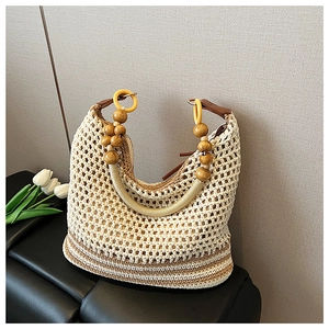 Detail of cream woven tote bag featuring dark wooden bead handles and crochet texture