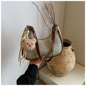 Detail of canvas crescent underarm bag with leather strap and plush bear charm