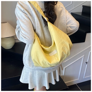Rear view of model wearing a bright yellow nylon half-moon crossbody bag with logo