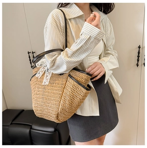 Détail du sac cabas en paille avec nœud en dentelle blanche et anses en cuir noir porté