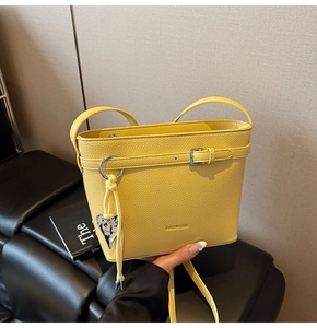 Detail view of yellow lychee texture bucket bag with silver buckle and leopard heart charm