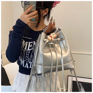 Chic silver bucket bag with bow detail and kitten charm shown in a mirror selfie