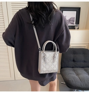 Détail du sac à bandoulière gris clair avec texture tissée et lanière en cuir