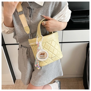 Detail of yellow quilted crossbody bag with adjustable strap and capybara charm