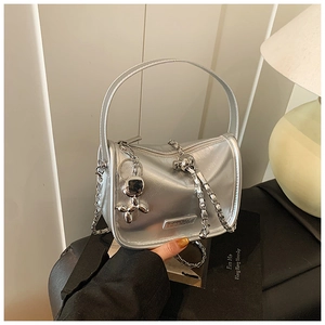Close-up of a silver crossbody bag with metal chain strap and cute balloon dog charm