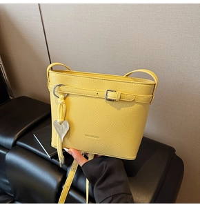 Detail of yellow lychee texture bucket bag with metal buckle and heart pendant
