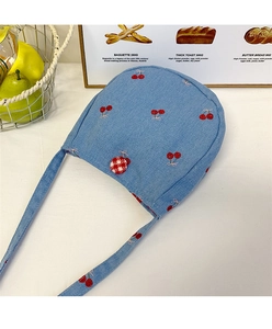 Détail du mini sac bandoulière en denim bleu clair avec broderie cerise et bouton damier