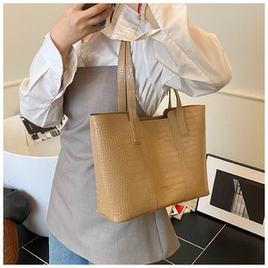 Detail view of khaki faux crocodile tote bag shown in a stylish lifestyle setting