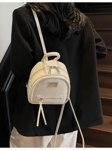 Minimalist beige mini backpack in glossy finish shown on model in a real-life scenario
