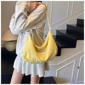 Close-up of yellow nylon crescent bag with adjustable strap and side pleated detail
