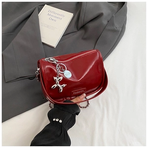 Close-up of red patent leather bag with silver chain and metal balloon dog charm