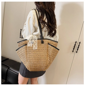 Détail du sac cabas en paille avec nœud en dentelle et poignée en cuir noir sur l'épaule