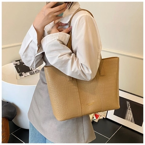 Beige crocodile embossed tote bag styled in a minimalist interior setting with a model