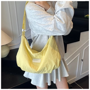 Close-up of bright yellow nylon dumpling bag with adjustable shoulder strap and logo